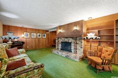 a living room filled with furniture and a fire place next to a book shelf on top of a green carpeted floor