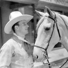 a man in a cowboy hat standing next to a horse