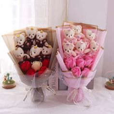 two bouquets with teddy bears in them on a table next to other flowers and figurines