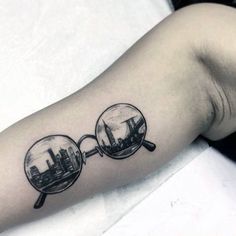 a person with a tattoo on their arm has a magnifying glass in the shape of a city