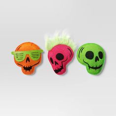 three halloween masks with green and orange hair, one has a skull on the forehead