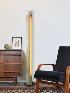 a black chair sitting next to a tall wooden cabinet on top of a carpeted floor