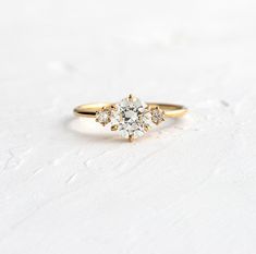 an engagement ring with three stones in the center on a white surface, one stone has been