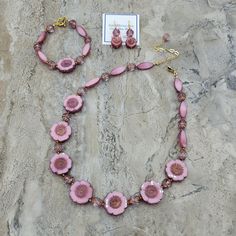 This "Pretty in Pink" 3 piece gift set features lovely, high quality glass beads made in the Czech Republic. The beads are soft pink and have a purple-bronze finish applied that is gorgeous. Crystal turbine beads with same purple bronze finish add an elegant pop to the jewelry set.  Antique gold spacer beads, components, and chain accent the Czech beads beautifully. NOTE that the little white dots you see in the photos are only reflections of the LED lights in the photo booth.  The short necklace length is adjustable from 18 to 21 inches.  Photos show short and extended lengths.  Bracelet is 8 inches long and finished with an antique gold toggle clasp. Earrings are 1 & 5/8 inches long and finished with gold filled hook ear wires.