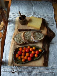 an assortment of bread, tomatoes and cheese on a cutting board