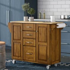 a kitchen island with wooden top and drawers on casteors in front of blue cabinets