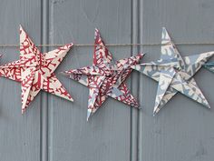 three red, white and blue origami stars hanging from a line on a gray wall