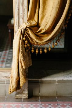 the curtain is open and hanging on the side of the building with tassels attached to it