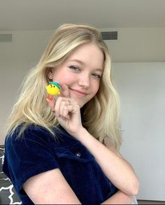 a woman holding a toy in her right hand and smiling at the camera with both hands