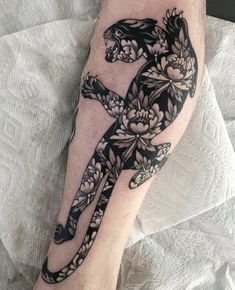 a person with a tattoo on their leg that has a cat and flowers on it