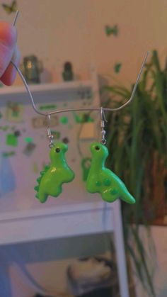 a pair of earrings with green plastic dinosaurs hanging from them