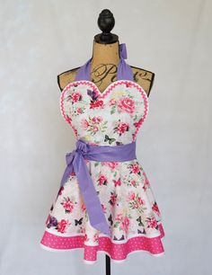 a dress on a mannequin with pink flowers and purple ribbon around the waist