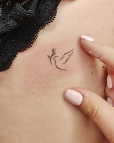 a woman's chest with a small bird tattoo on it