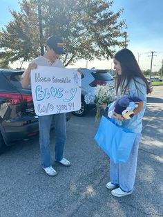 two people standing next to each other holding signs