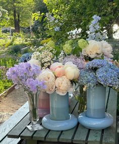 three vases filled with flowers sitting on top of a wooden table next to each other