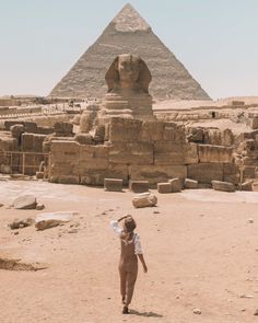 a woman is standing in front of the pyramids