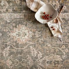 an old rug with some red berries on it next to a white plate and spoon