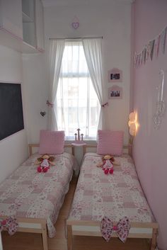 two twin beds in a small room with pink walls