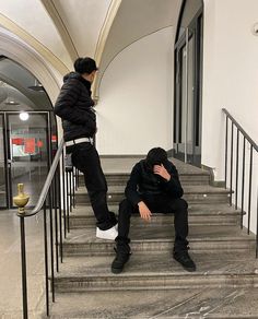 two men are sitting on the stairs and one is holding his head in his hands