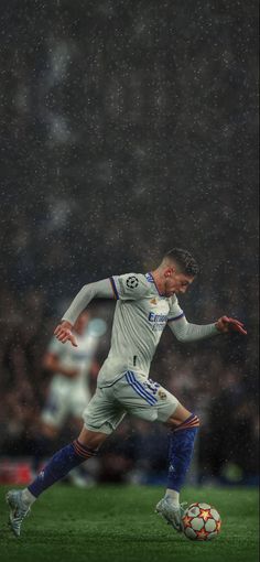 a soccer player is running with the ball in his hand during a rain soaked game