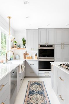 a kitchen with white cabinets and an area rug on the floor in front of the stove