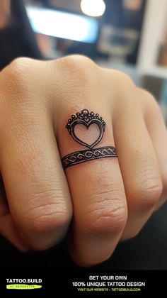 a woman's hand with a heart tattoo on her left wrist and a black band around the ring