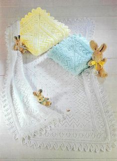 three stuffed animals laying on top of a white crocheted blanket next to each other