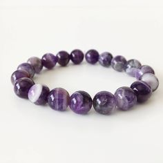 "Amethyst Natural Stone Bracelet Approx. 7\" circumference, on flexible cord. Each piece is unique and hand made by me. Bracelet is made out of natural Amethyst beads and is available with either 10mm or 8mm beads on a flexible cord. These beautiful round beads are stunning and full of luster. One of my favorites, looks amazing with the white coral bracelet: https://www.etsy.com/listing/113321708/white-coral-bracelet-natural-stones Because we are dealing with natural stone beads, color variation Purple Amethyst Bracelet With Round Beads, Purple Beaded Amethyst Crystal Bracelet, Purple Amethyst Round Stretch Bracelet, Purple Natural Stones Beaded Bracelet - Gift, Elegant Hand-strung Amethyst Beaded Bracelets, Natural Stone Beads, 8mm Beads, Coral Bracelet, White Coral