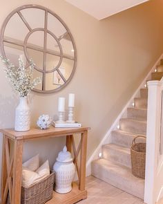 a wooden table sitting under a mirror next to a stair case with vases on it