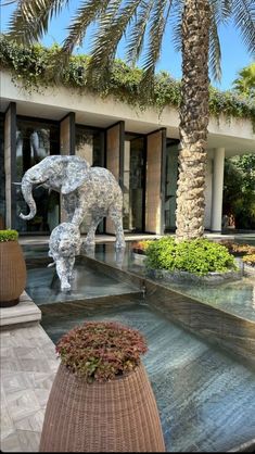 an elephant statue in the middle of a courtyard with palm trees and potted plants