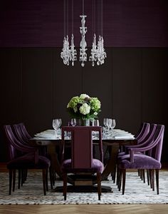 a dining room table with purple chairs and chandelier