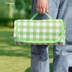 a person holding a green and white checkered bag in their hand, with grass behind them