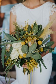 a bride holding a bouquet of flowers and greenery