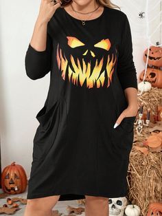 a woman wearing a black dress with an orange and yellow pumpkin face on the front