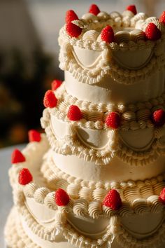 a three tiered cake with raspberries on the top is white and has red icing