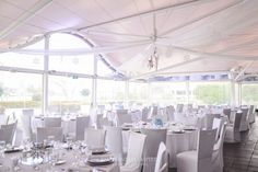 tables and chairs are set up in a tented area for a formal function with white linens