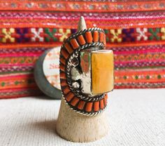 This is a Magnificent Tibetan ethnic ring, it was designed on a model of old traditional Tibetan jewelry. It is entirely handmade. This is a rare piece (limited quantity). It is made of Tibetan silver inlaid with coral and amber resin. It is very bright. This is a very large ring. Length of the ring: 4.2 cm Width of the ring: 2.5 cm Ring weight: 34 grams Does not contain nickel, lead or cadmium. It will be shipped in a small pouch. Shipping will be fast and careful. Visit the NEPALMASHOP.FR stor Traditional Carved Rings For Ceremonial Occasions, Traditional Carved Ceremonial Rings, Traditional Orange Gemstone Jewelry, Vintage Handmade Rings For Ceremonial Occasions, Traditional Handmade Rings For Festival, Bohemian Orange Jewelry Ring, Bohemian Handmade Collectible Rings, Traditional Gemstone Rings For Collectors, Orange Handmade Jewelry For Ceremonial Use