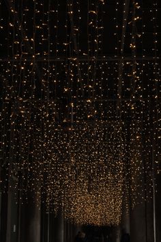 people walking down a dark hallway covered in lights