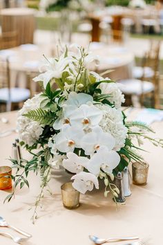 white flowers and greenery decorate the centerpieces of this elegant wedding reception table