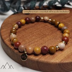 MOOKAITE JASPER BEADED BRACELET WITH 14KT GOLD FILLED ACCENTS HEALING PROPERTIES: Mookaite Jasper is thought to be a physically stabilizing stone, it brings well-being, strengthening the immune system, heals wounds and purifies the blood. Mookaite is believed to be a healing stone of Mother Earth, containing sacred earth energies that can be harnessed for healing the plane. DESIGN: 6mm natural stones with 14kt gold filled spacers and charm. Each gemstone bracelet comes with a FREE ESSENTIAL OIL DIFFUSER BRACELET! These are made of either natural lava stones or rosewood. We aim to pair the color of the complimentary essential oil bracelet to your unique bracelet's characteristics, but if you want lava stone more than rosewood (or vice versa) just leave us a message in "Note to Seller."  MAT Gold Bracelets With Polished Beads For Healing, Gold Stretch Bracelet With Natural Stones For Everyday, Spiritual Brown Hypoallergenic Jewelry, Brown Hypoallergenic Spiritual Jewelry, Hypoallergenic Brown Spiritual Jewelry, Everyday Hypoallergenic Brown Jewelry, Reminder Bracelets, Oil Bracelet, Sacred Earth