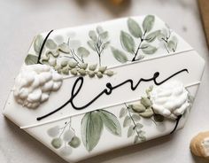 a white plate with flowers and the word love written on it next to some cookies