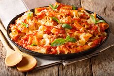 a pan filled with pasta and sauce on top of a wooden table