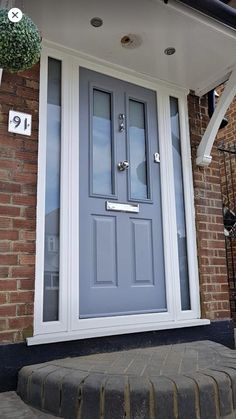 a blue front door on a brick house with white trim and glass panels that lead into the entrance