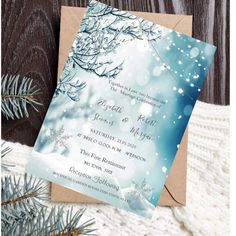 a wedding card with snowflakes on it and pine branches in the foreground