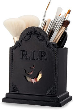 a black holder with makeup brushes in it and the word r i p on it