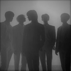 the silhouettes of four men standing in front of a foggy background with one man looking at something