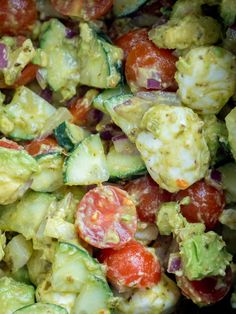 a salad with cucumbers, tomatoes and other vegetables is shown in close up