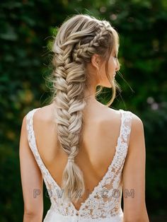 a woman with long hair in a fishtail braid wearing a wedding dress and looking back