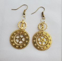 This pair of earrings is made from gold gears connected by jump rings with a gear inside another gear that spins just enough to add some extra dimension (but not entirely 360 degrees)! Perfect for everyday wear or to give a little extra pizzazz to your cosplay! Earrings come with backs attached. I buy quality materials but cannot personally attest that they are 100% allergen free for people with certain metal sensitivities. They are lightweight so as not to strain your earlobes or stretch your h Gold Steampunk Jewelry Made Of Copper, Steampunk Gold Dangle Jewelry, Gold Steampunk Jewelry With Copper, Gold Steampunk Dangle Jewelry, Handmade Steampunk Gold Earrings, Handmade Gold Steampunk Earrings, Gold Steampunk Earrings, Gold Steampunk Nickel-free Jewelry, Steampunk Earrings