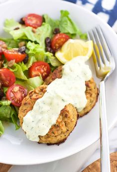 a white plate topped with meat patties and salad